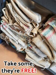 two stacks of burlap coffee sacks with text "take some they're free" on it.