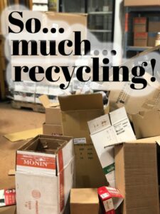 Big pile of cardboard with words "So Much Recycling" in front of it