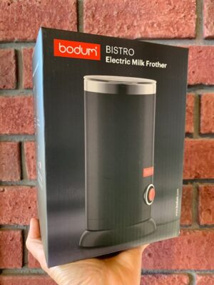 Bodum Bistro Electric Milk Frother in front of a brick wall