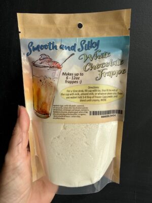 A hand holding a bag of white chocolate frappe power, or white hot chocolate powder