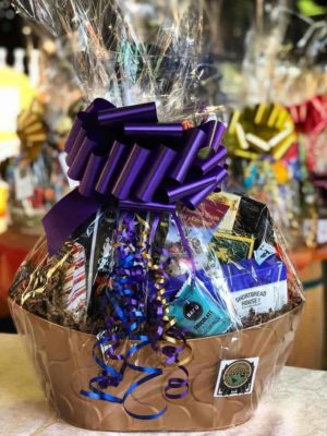 Large gift basket full of food products and coffee, with a large purple bow.