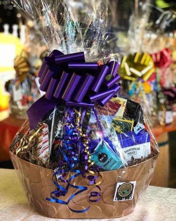 Large gift basket full of food products and coffee, with a large purple bow.