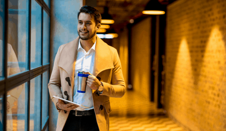 employee in an overcoat in a hallway with a cup of coffee