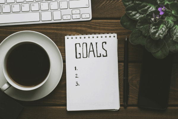 overhead shot of fundraising goals checklist on a desk with a cup of coffee, keyboard, pen and African violet