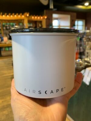 Hand holding a matte white metal short Airscape canister with a smoked acrylic lid