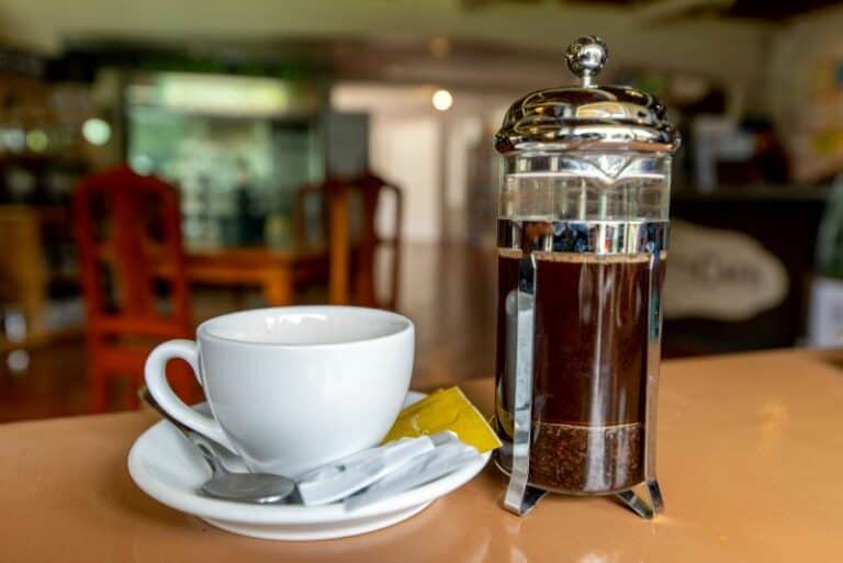 White coffee mug and saucer with a full French press in a store