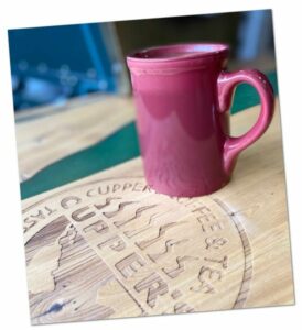 Red mug of tea on Cupper's logo board