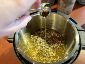 Instant pot of tea leaves and water with honey pouring from a spoon