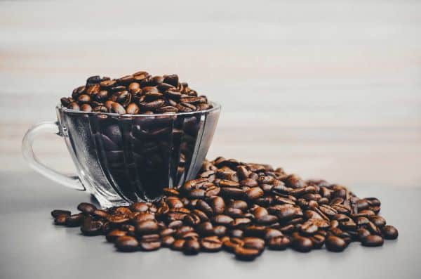 Clear coffee cup with beans in and around it