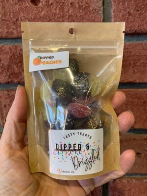 Fuzzy peach candies dipped in chocolate and sparkles, made by Dipped & Drizzled