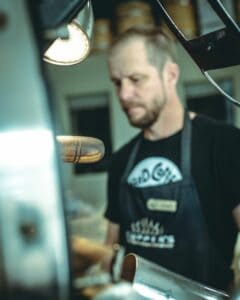 Josh in background, coffee roaster and tamper in front of him