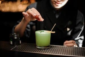 A chef putting finishing touches on a Pistachio Gin Sour for a cocktail recipe.