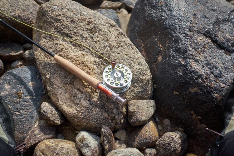 Fly fishing Rod and reel on river rocks