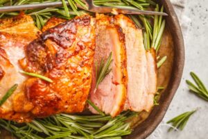 Roasted Peach & Pepper pork tenderloin on a plate with rosemary