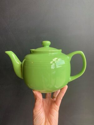 Mojito Green 6 cup Windsor Teapot being held up by a hand in front of a blackboard