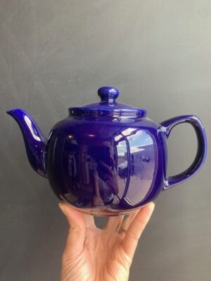 Royal Blue 6 cup Windsor Teapot being held up by a hand in front of a blackboard