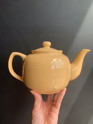 Sahara 6 cup Windsor Teapot being held up by a hand in front of a blackboard