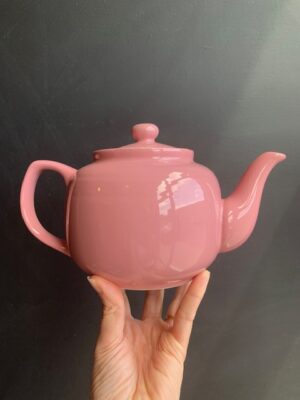 Sierra Rose 6 cup Windsor Teapot being held up by a hand in front of a blackboard