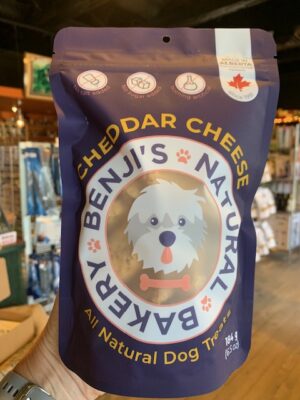 A large purple bag of Benji's Cheddar Cheese Dog Treats being held by a hand at Cupper's Coffee & Tea.