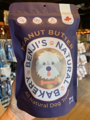 A large purple bag of Benji's Peanut Butter Dog Treats being held by a hand at Cupper's Coffee & Tea.