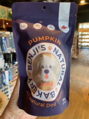 A small purple bag of Benji's Pumpkin Dog Treats being held by a hand at Cupper's Coffee & Tea.