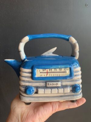 blue radio Teapot made by Blue Sky being held by a hand