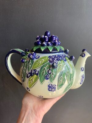 blueberries Teapot made by Blue Sky being held by a hand