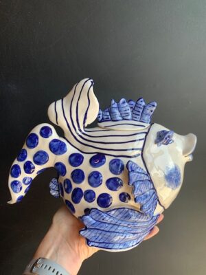 Blue Delft Fish Teapot made by Blue Sky being held by a hand