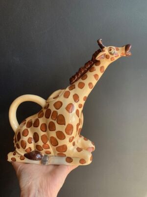 Giraffe Teapot made by Blue Sky being held by a hand