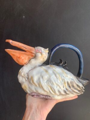 Pelican Teapot made by Blue Sky being held by a hand