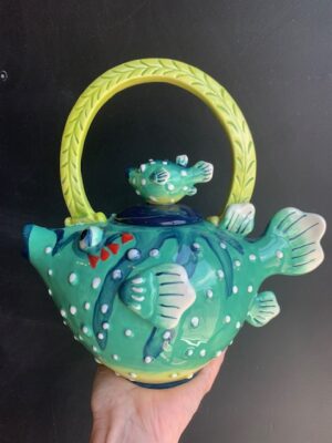 Puffer Fish Teapot made by Blue Sky being held by a hand