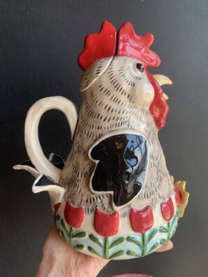 Roo Rooster Teapot made by Blue Sky being held by a hand