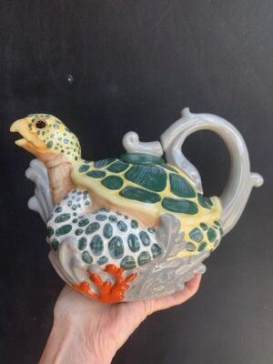 Sea Turtle Teapot made by Blue Sky being held by a hand