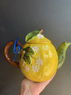 Cottage Lemon Teapot made by Blue Sky being held by a hand