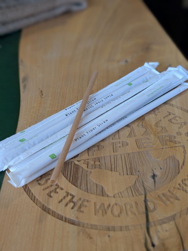 A stack of paper covered plant based beverage straws on a Cupper's wooden counter