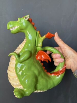 a hand holding a Blue Sky Clayworks Sitting Green Dragon Teapot