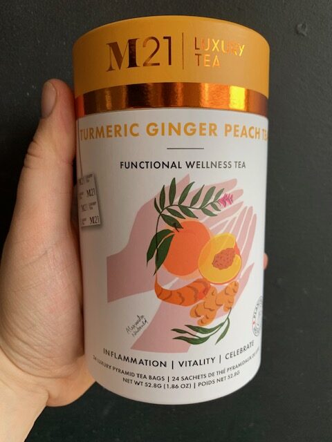 M21 Turmeric Ginger Peach Tea being held by a hand