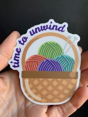 Sticker with basket of yarn and knitting needles, and text "time to unwind"