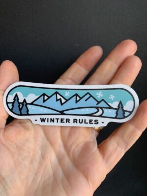 sticker with a snowboard that shows a snowy mountain scene with text 'winter rules'