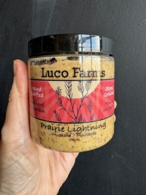 Luco Farms Prairie Lightning mustard in a plastic jar, being held by a hand