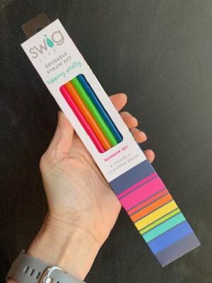 Swig Rainbow reusable straw set with brush being held by a hand