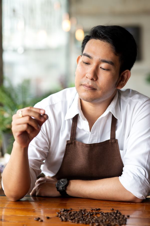 A man looking at individual coffee beans for freshness