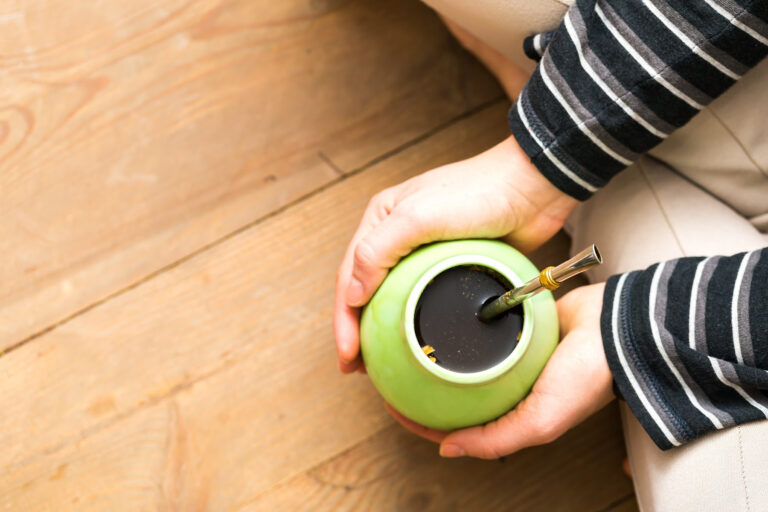 hands holding a gourd for brewing yerba mate, with a bombilla in it.