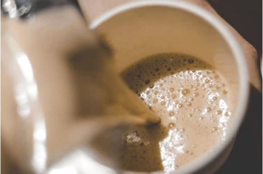 Coffee with cream in it being poured in a paper cup