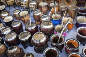 Many yerba mate gourds full of tea with bombilla straws on a table,