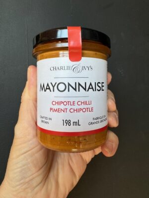 A hand holding a jar of Charlie & Ivy Chipotle Chili Mayonnaise