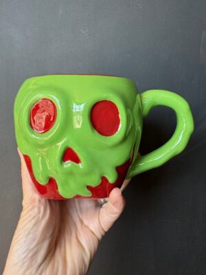 a Hand holding a Disney Snow White Poison Apple mug