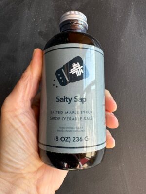 a hand holding a bottle of Dript Salty Sap Maple Syrup