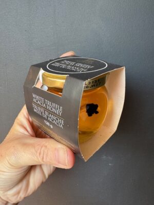 a hand holding a jar of Truffle Hunter white truffle honey