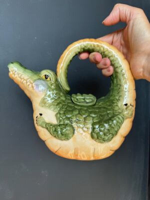 a hand holding a Blue Sky Clayworks Alligator Teapot